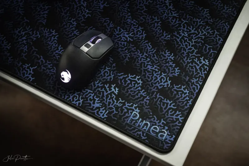 Motif PINEA bleu sur la surface d’un tapis de bureau sous une souris